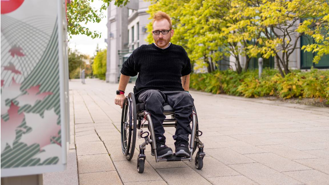 Un homme en fauteuil roulant s’approche d’une boîte postale communautaire accessible Un homme en fauteuil roulant s’approche d’une boîte postale communautaire accessible